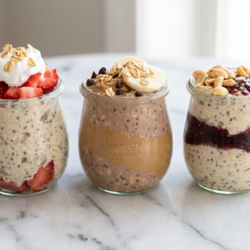 Creamy protein overnight oats with protein powder, topped with fresh raspberries, blueberries, and chopped nuts in a glass jar.