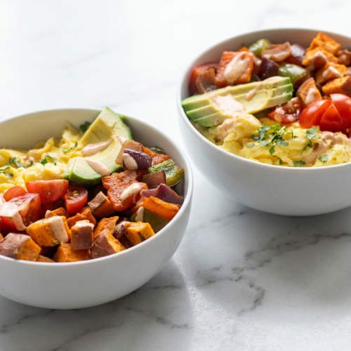 Tex mex protein breakfast bowls topped with scrambled eggs, black beans, avocado, sweet potato, and a creamy chipotle-lime crema.