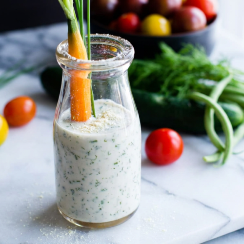 Creamy greek yogurt ranch dressing in a white ceramic bowl, garnished with fresh chives and dill.