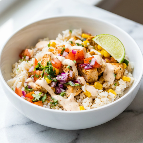 A healthy chicken taco bowl loaded with seasoned chicken, brown rice, black beans, corn, and fresh pico de gallo, drizzled with smoky chipotle-lime crema.