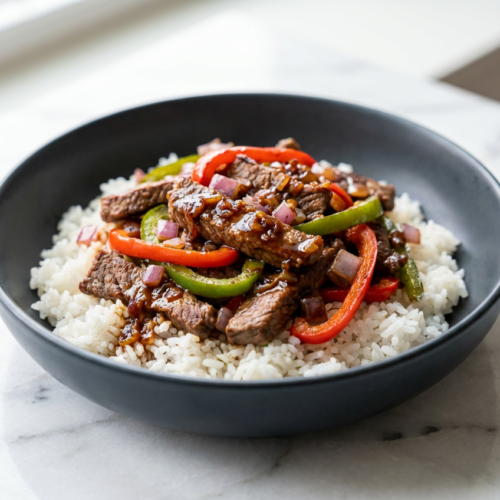 A colorful high protein beef and pepper rice bowl with lean ground beef, bright bell peppers, and a rich, glossy pan sauce over fluffy rice.