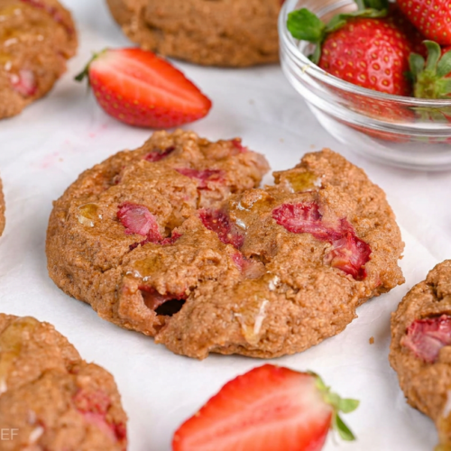 Stack of golden-brown protein greek yogurt cookies, some with melted chocolate chips, on a cooling rack.