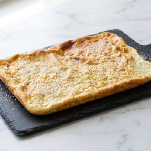 Golden-brown two ingredient cottage cheese flatbread, flexible and ready to be folded, served on a neutral surface.